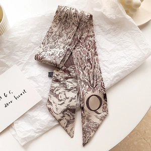 Détail d'un twilly en soie beige avec illustrations vintage et lettre Q imprimée