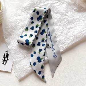 Dettaglio di un foulard sottile in raso con stampa floreale di mirtilli e testo
