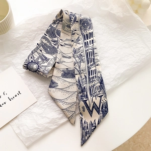 Foulard étroit en satin bleu et blanc avec motif lettre W posé sur papier plissé