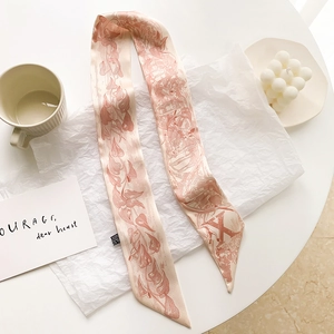 Gros plan détaillé d'un foulard étroit en soie avec motifs floraux et la lettre X