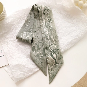 Détail de l'écharpe en soie verte avec motifs floraux et lettre Y imprimée élégante