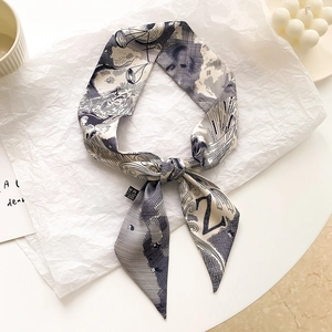 Détail macro d'un foulard étroit en soie avec imprimés célestes noirs et blancs et étiquette