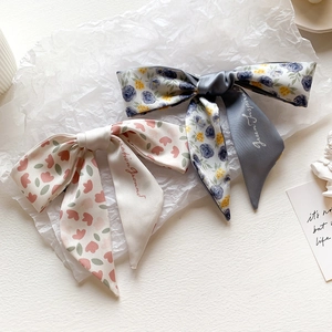 Detail of floral tie-dye faux silk hair scarf with elegant bow and printed ribbons