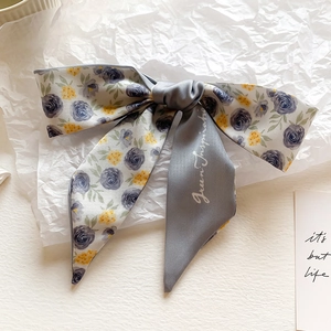 Detail of faux silk scarf featuring blue roses and Green Inspiration text on satin fabric
