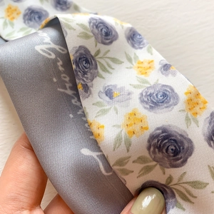 Detail of silk-like tie-dye scarf featuring floral rose patterns and artistic lettering