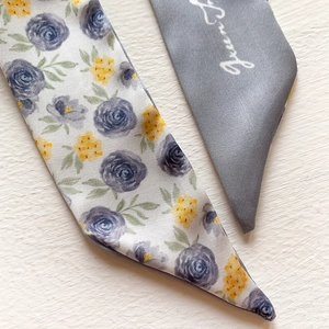 Detailed view of tie-dye silk twill scarf with blue floral print and gray logo side