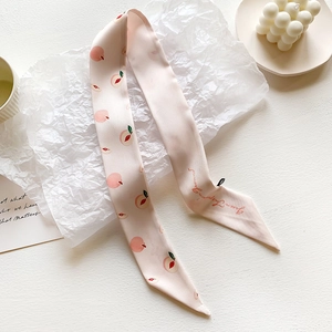 Detail of light pink silk scarf featuring peach patterns and handwritten text decor