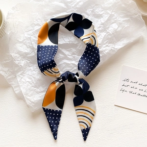 Close-up of artistic silk scarf with navy and orange geometric patterns on textured white base