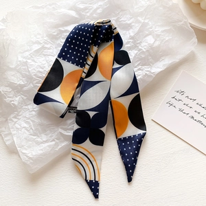 Detail of artistic tie-dye silk scarf with navy dots and orange geometric floral patterns