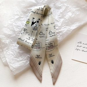 Detail of a beige twilly silk scarf featuring hand-drawn cartoon illustrations and text