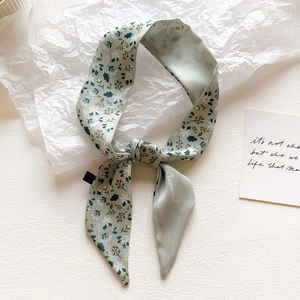 Detailed bow-tie knot of a floral tie-dye silk twilly scarf in soft sage green finish