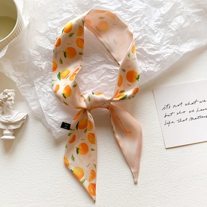Pink satin ribbon scarf with orange prints tied as a bow on an elegant white background