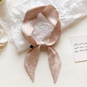 Detailed macro view of a floral silk scarf with pink flower patterns and elegant texture