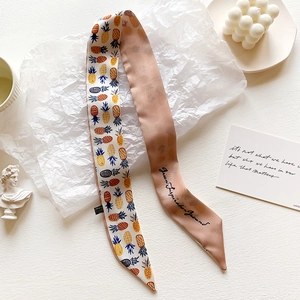 Detail of a tie-dye silk twilly with pineapple print and elegant script on light pink background
