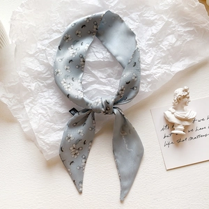 Detail view of light blue floral faux silk scarf with elegant knotting and soft textures