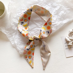 Detail of silk-like neck scarf with colorful fruit prints and handwritten typography