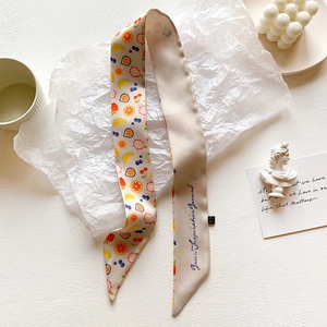 Detailed shot of long silk-feel scarf with colorful fruit prints on a white aesthetic background