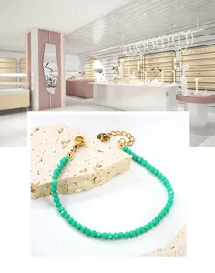 Détail macro du bracelet perlé vert avec fermoir mousqueton doré et chaîne réglable