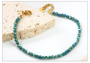 Détail d'un bracelet en perles vert paon avec fermoir et étiquette en acier inoxydable doré