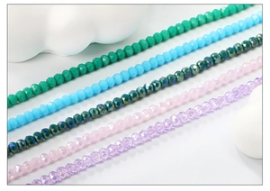 Gros plan de perles en cristal facettées en vert, bleu, rose et violet sur décor blanc
