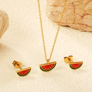 Cute gold watermelon jewelry set with necklace and stud earrings on textured background