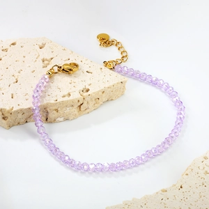 Bracelet en cristal facetté lavande avec fermoir doré sur support en pierre beige