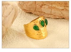 Détail d'un bracelet manchette martelé doré orné de trois pierres vertes en poire