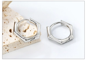 Détail macro de boucles d'oreilles hexagonales argentées sur un support en pierre