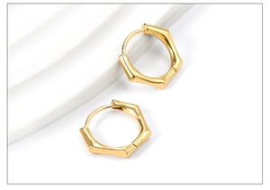Détail macro de boucles d'oreilles hexagonales dorées avec texture bambou polie