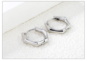 Vue détaillée des boucles d'oreilles hexagonales argentées avec motif bambou poli