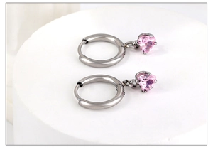 Détails des boucles d'oreilles cœur argentées avec zircon rose sur support blanc