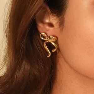 Élégantes boucles d'oreilles nœud en acier inoxydable doré 18 carats sur mannequin