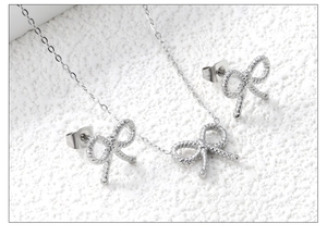 Ensemble de bijoux nœud argenté avec collier et boucles d'oreilles sur fond texturé