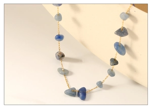 Detailed close-up of colorful irregular stone charms on a minimalist gold-tone chain necklace