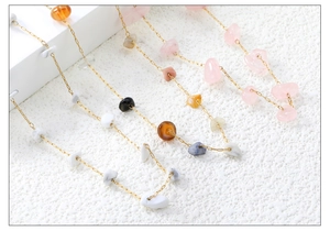 Close-up of colorful natural irregular gravel stones on a golden stainless steel chain
