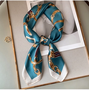 Vue détaillée d'un foulard en soie bleue avec motifs de chaînes dorées sur cadre
