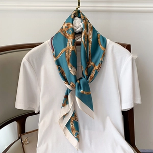 Détail d'un foulard carré en soie bleu canard avec chaînes dorées et motifs équestres