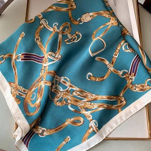 Vue détaillée du foulard en soie bleu paon avec imprimés équestres dorés et boucles
