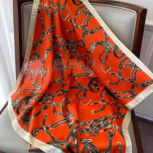 Détail de l'écharpe en soie orange avec motif équestre de chaînes et de mors en gros plan