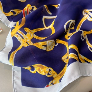 Gros plan d'un foulard en soie avec motif de chaîne dorée sur fond bleu marine élégant