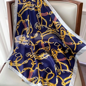 Détail d'un carré de soie satinée avec motifs de chaînes dorées et bleu marine