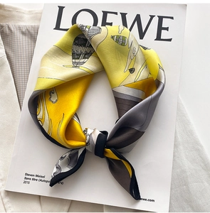Detail of silk scarf with hot air balloon print and fine black hem on magazine background