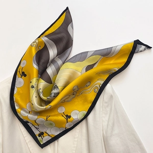 Detail of silk scarf with yellow and grey wavy patterns on a white blazer