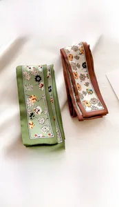 Detail view of 5.5x118cm silk-like twilly scarves with floral print in green and brown
