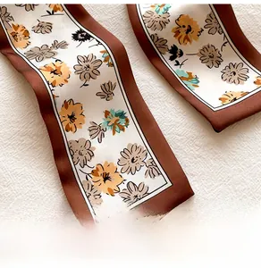 Detailed close-up of floral print silk scarf featuring a brown border and daisy pattern