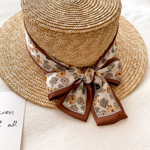 Flat top straw sun hat with floral print silk ribbon bow for a stylish beach holiday