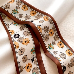 Close-up of floral print silk scarf with retro daisy patterns and brown borders