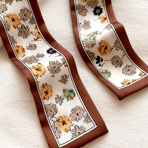 Close-up of vintage daisy print on ivory satin twilly scarf with brown border detail