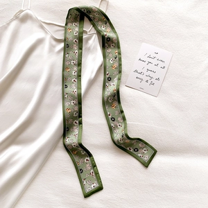 Close-up of olive green floral silk scarf paired with a sleek white satin slip dress