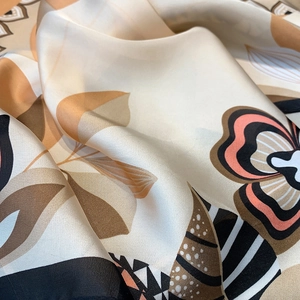 Close-up of elegant floral print on high-quality satin silk scarf showing smooth texture